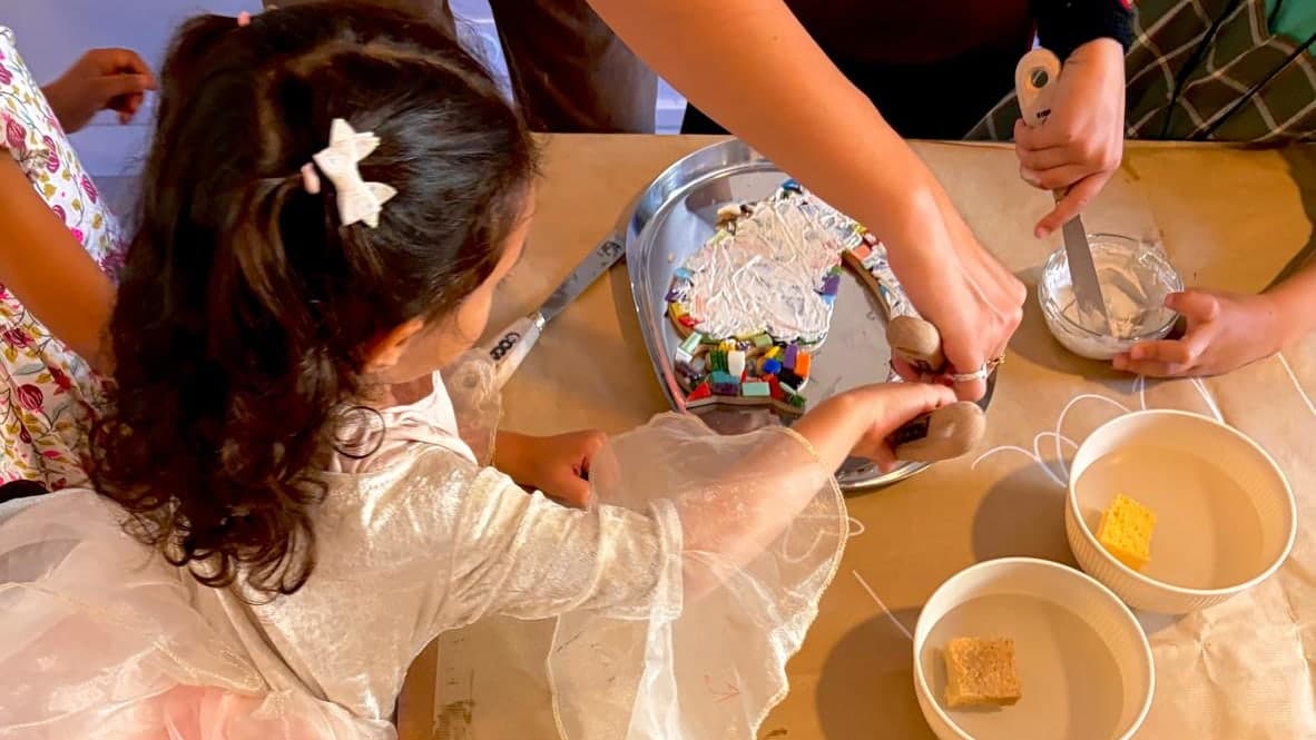 Un anniversaire à l'atelier : les enfants assemblent leur mosaïque, vus de dessus