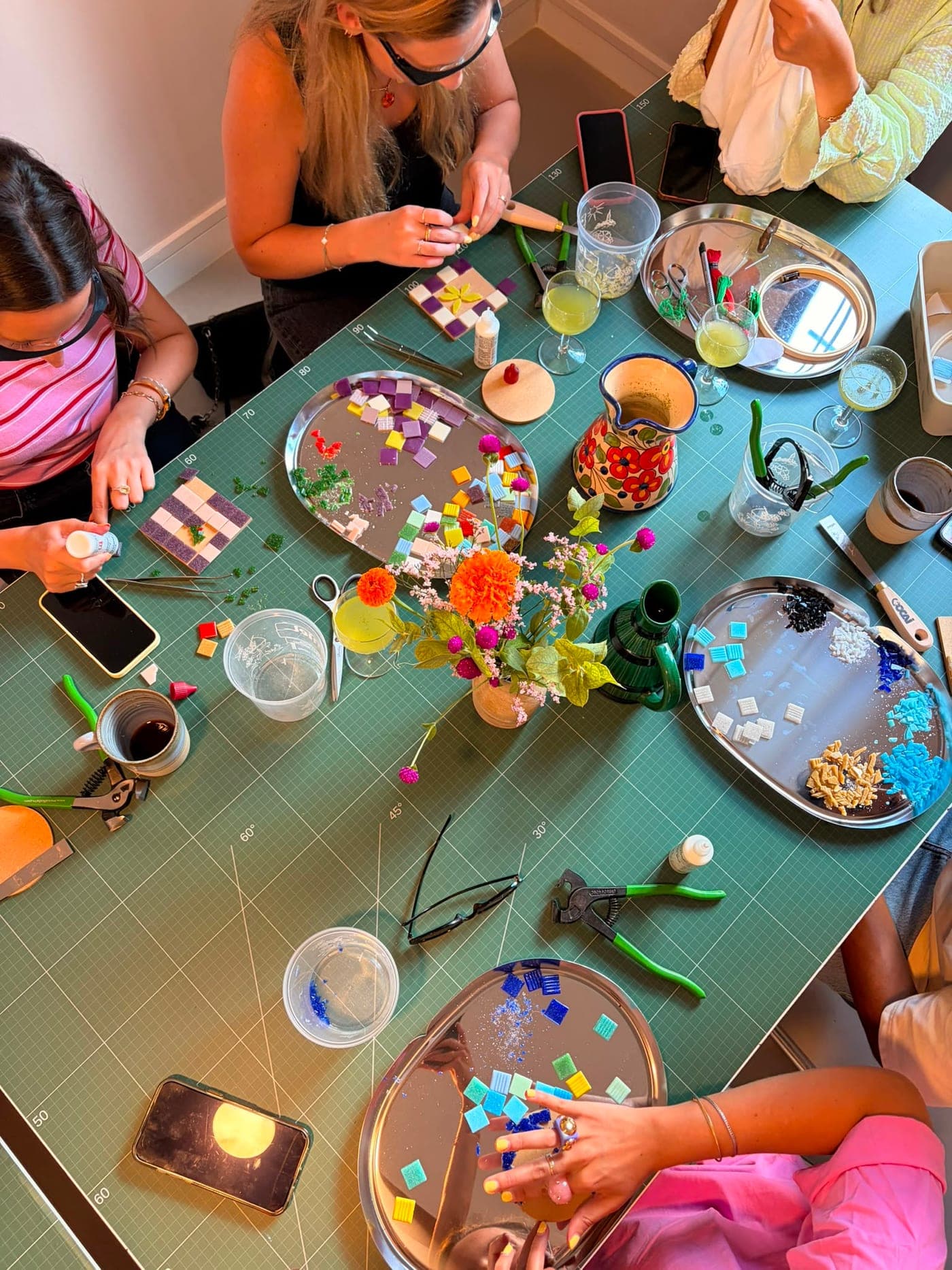 Une table pendant une session mosaïque, plateaux de tesselles et bouquet